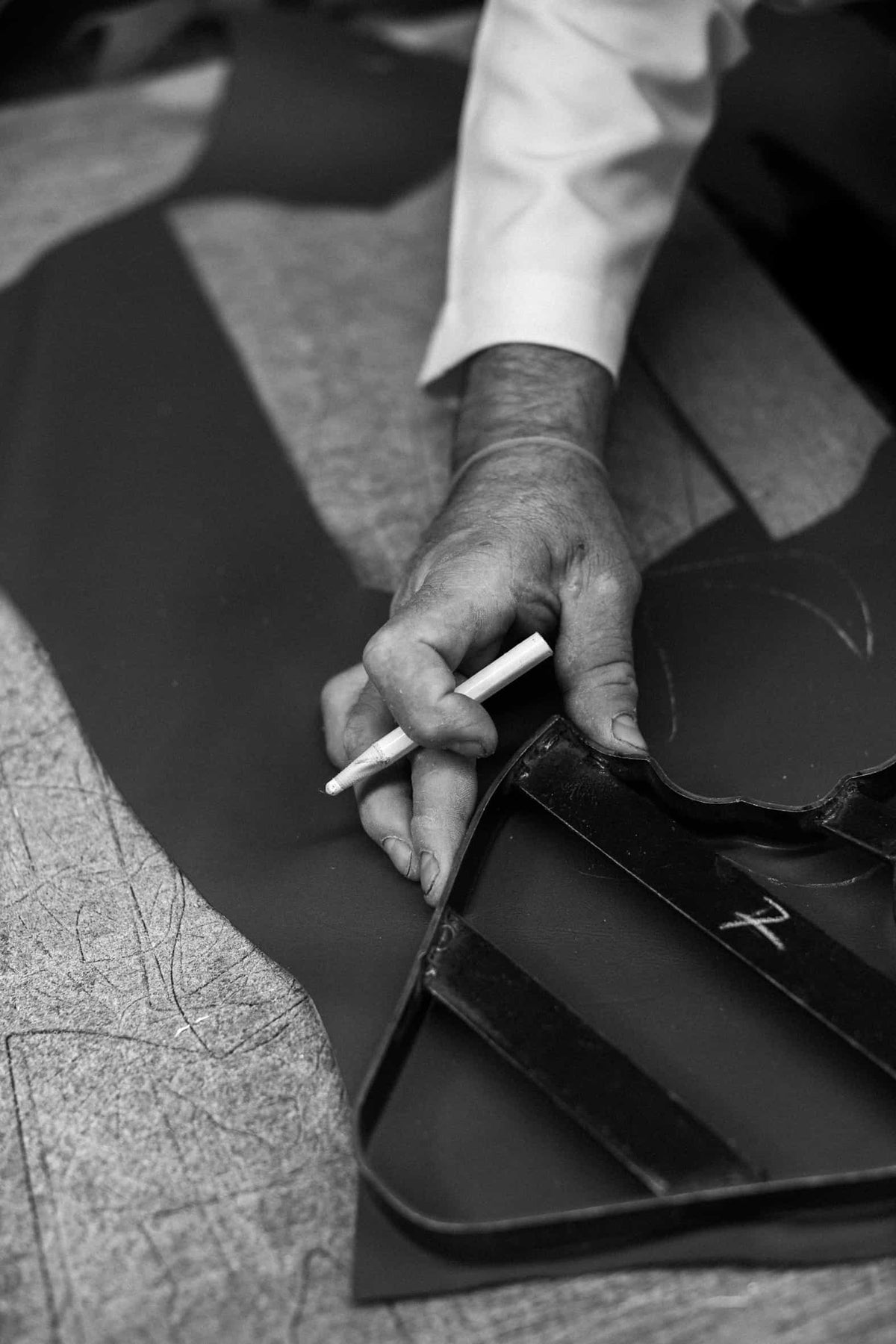 Artisan tracing a pattern on black leather, in black and white