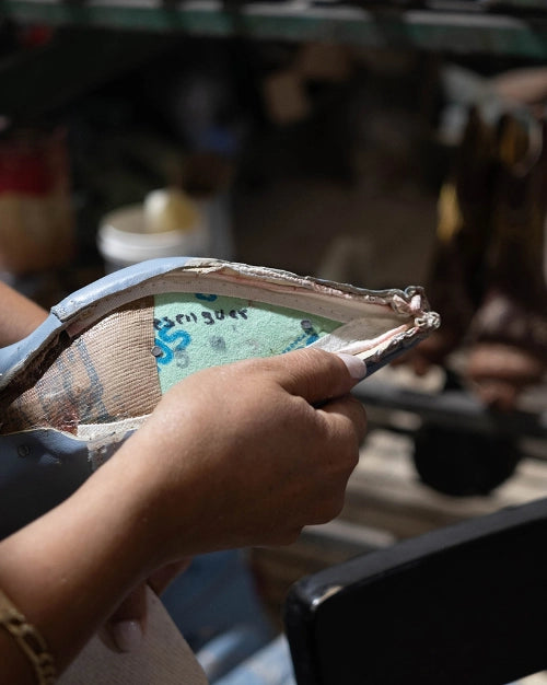 Hands holding a piece of embroidered leather in the workshop