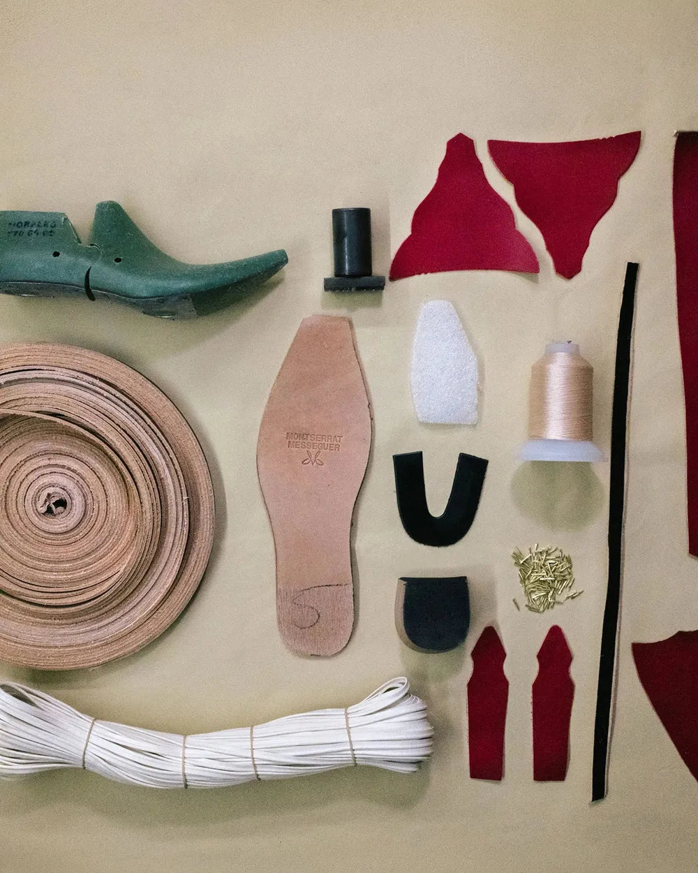 Lasts, leather pieces, threads and tools for making a boot, laid out on a table
