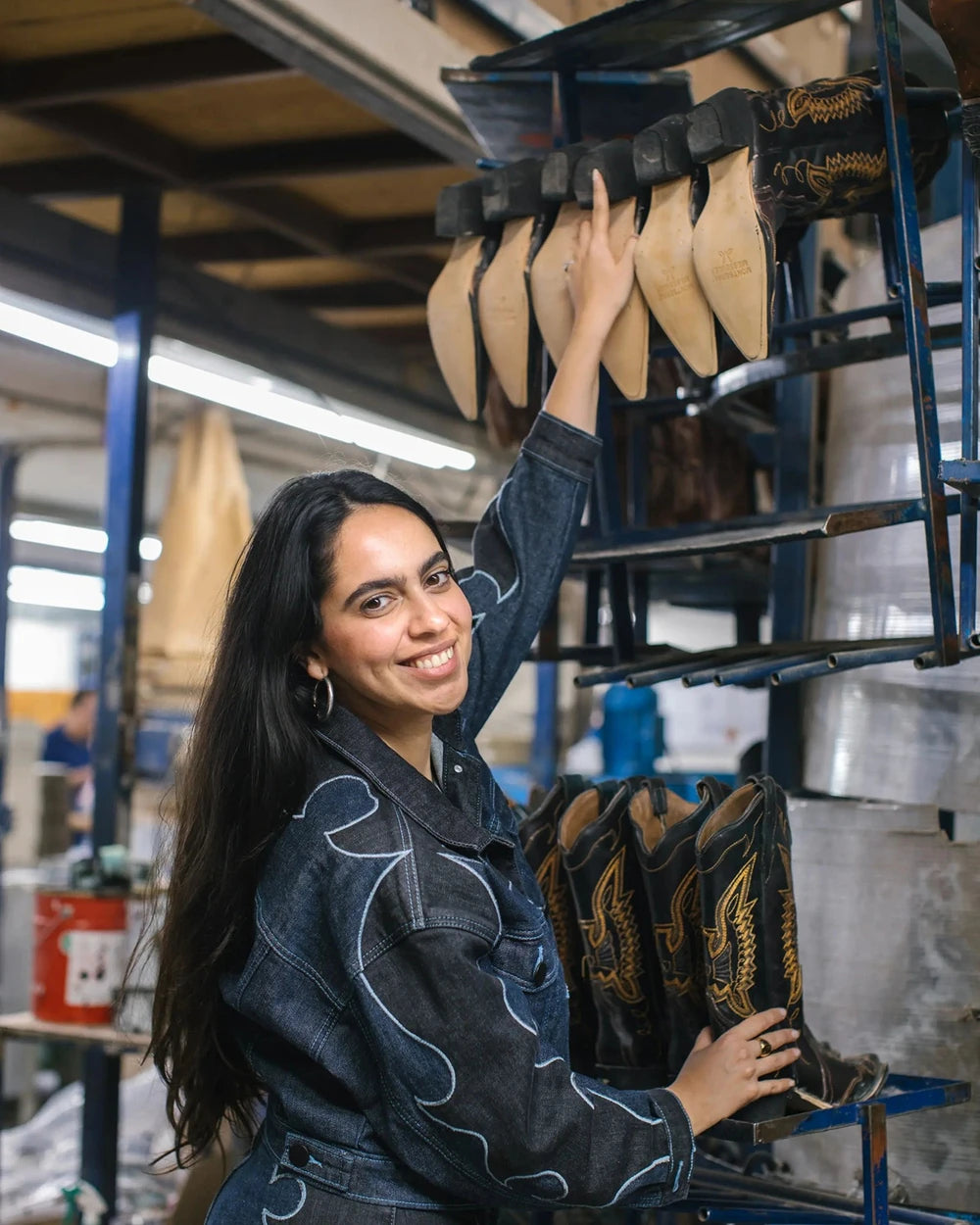 Montserrat Messeguer smiling beside a rack of boots in the workshop