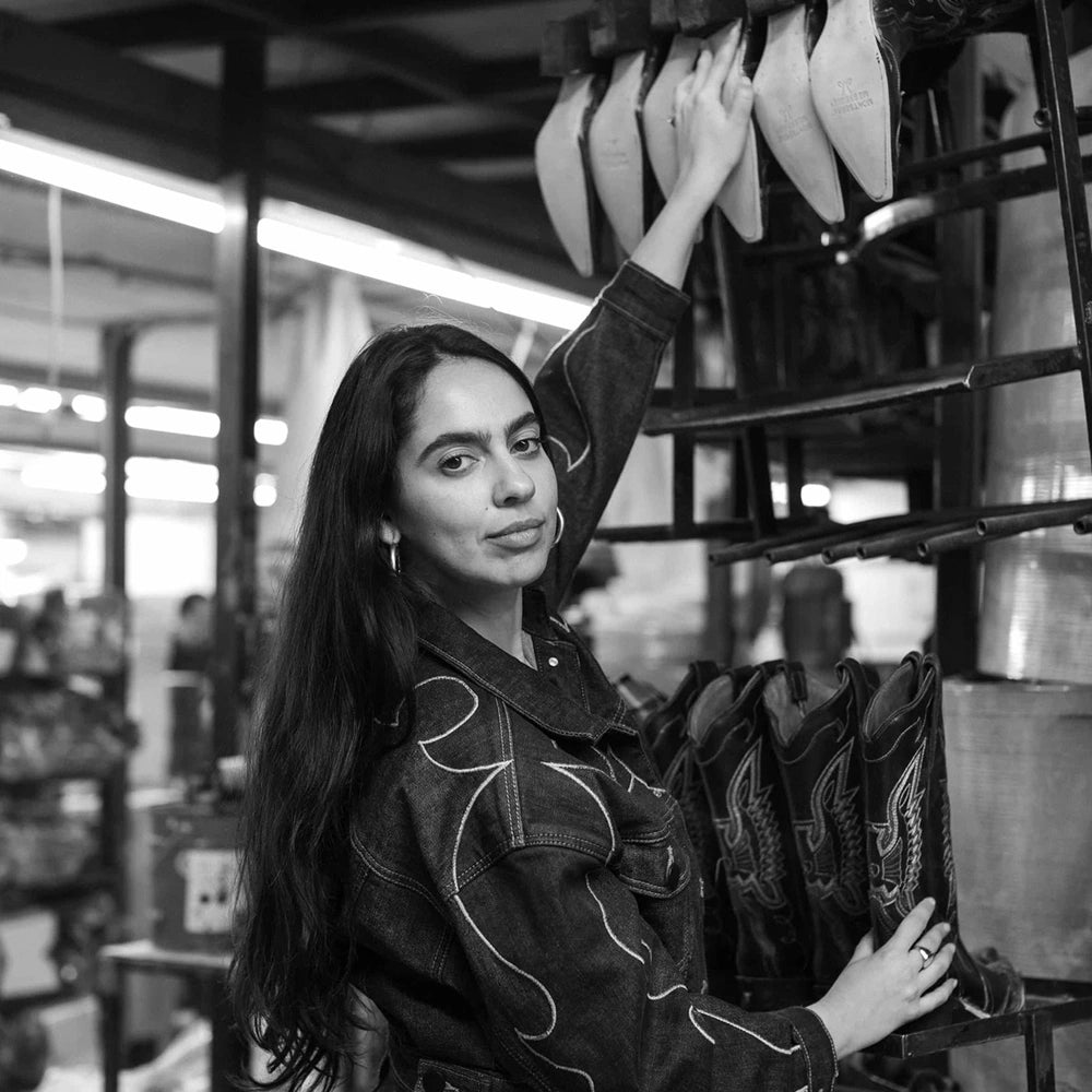 Montserrat Messeguer in the workshop, beside a rack of lasts and boots, in black and white