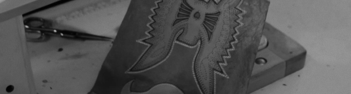 Detalle del bordado del ave fénix en la caña de una bota, en blanco y negro